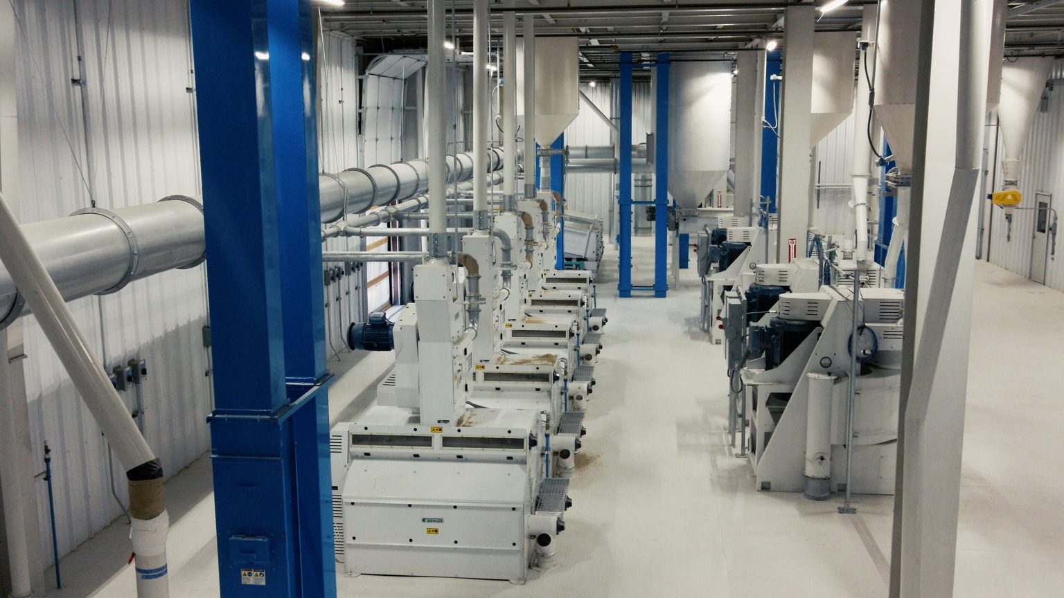 Rice mill interior: a row of Bühler sifter units along the aisle.